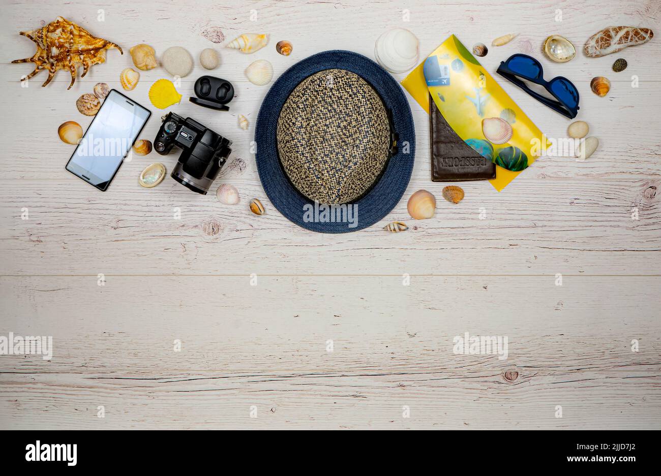 Accessori per le vacanze sulle tavole di legno lite. Posizione: Centrata nella parte inferiore. Cappello da viaggio, macchina fotografica, portadocumenti con passaporto, occhiali da sole, smart Foto Stock