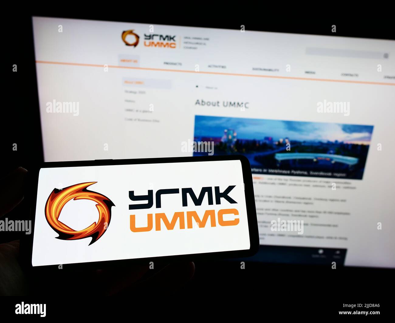 Persona che tiene smartphone con il logo di Ural Mining e Metallurgical Company (UMMC) sullo schermo di fronte al sito web. Mettere a fuoco sul display del telefono. Foto Stock