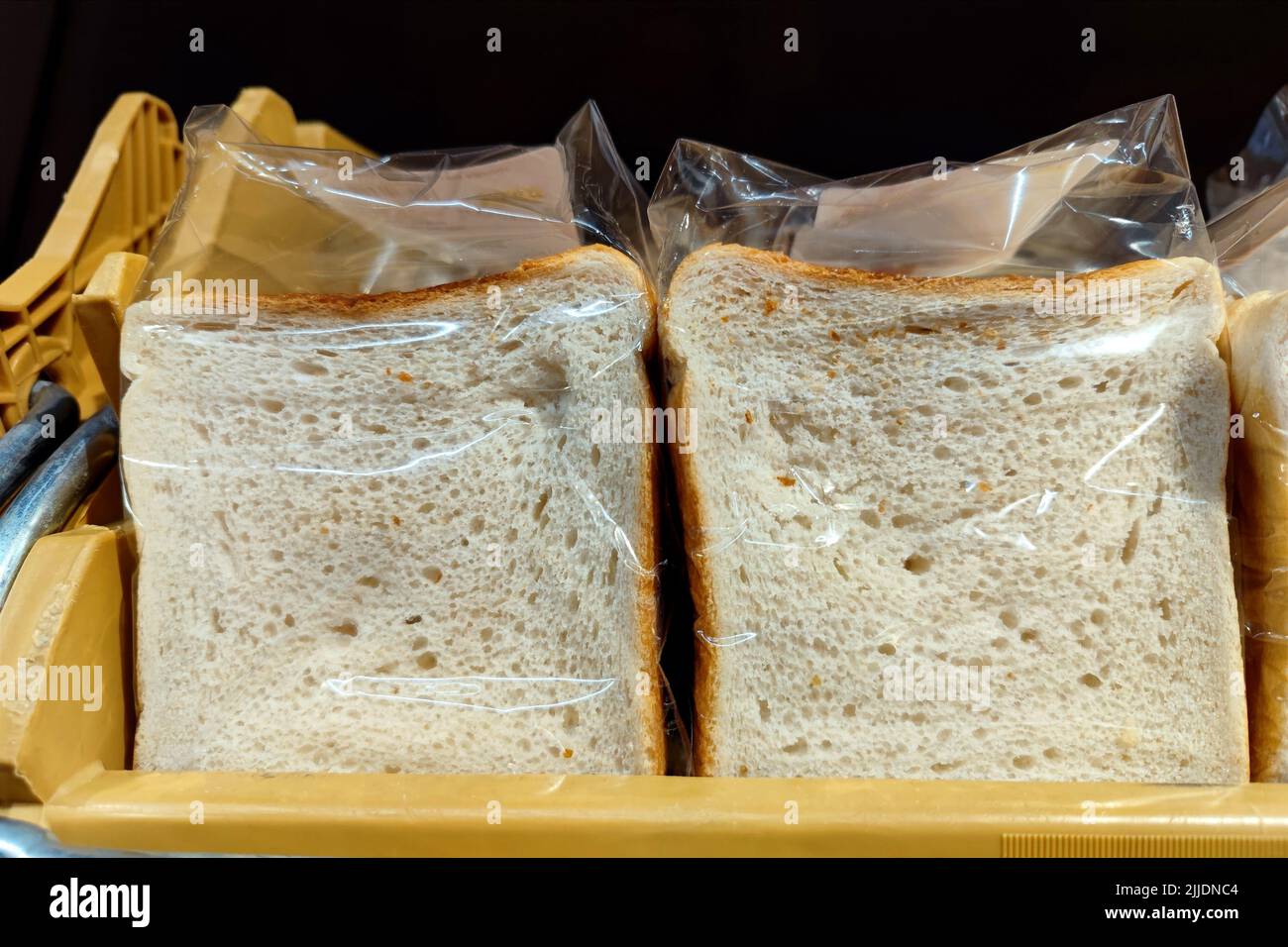 Fette di pane bianco non branded avvolte in plastica sono su un ripiano del supermercato pronto per essere venduto Foto Stock