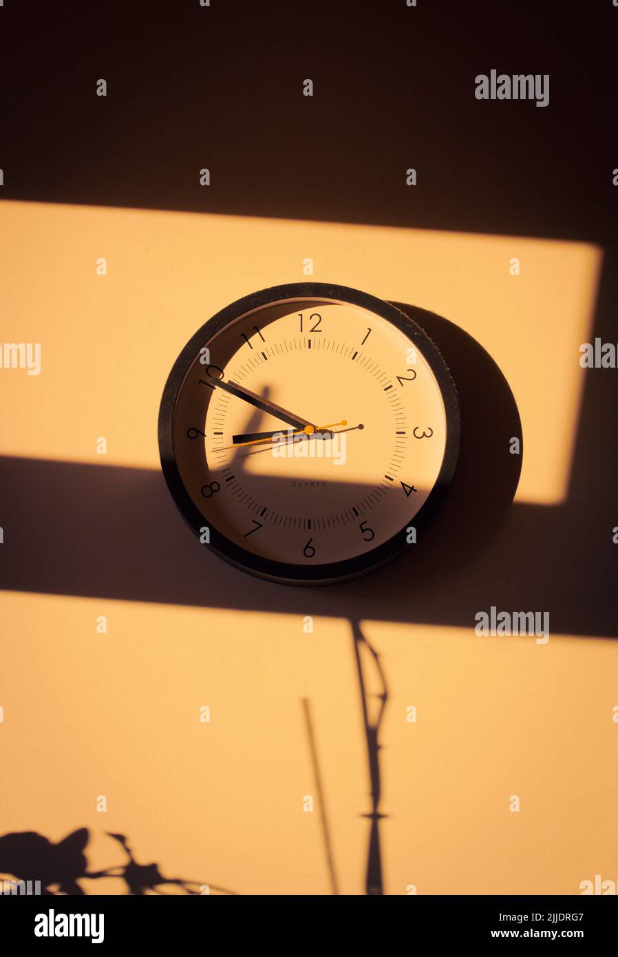 Un orologio da cucina in luce solare calda e ombre. Foto Stock