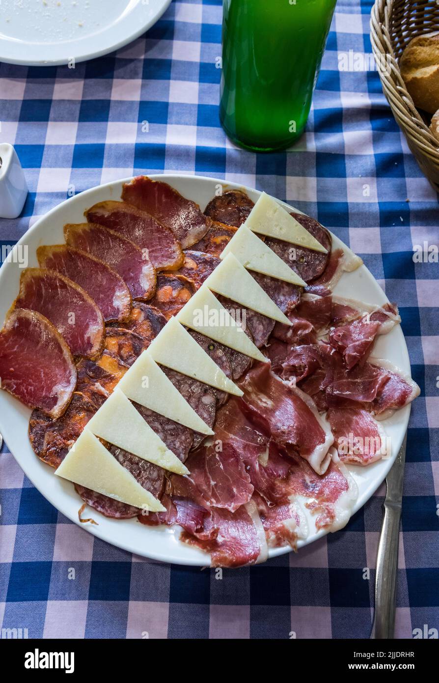 Una deliziosa tavola di tapas di carni crude di maiale e formaggio di pecora con una tradizionale bottiglia di sidro asturiano sul lato Foto Stock