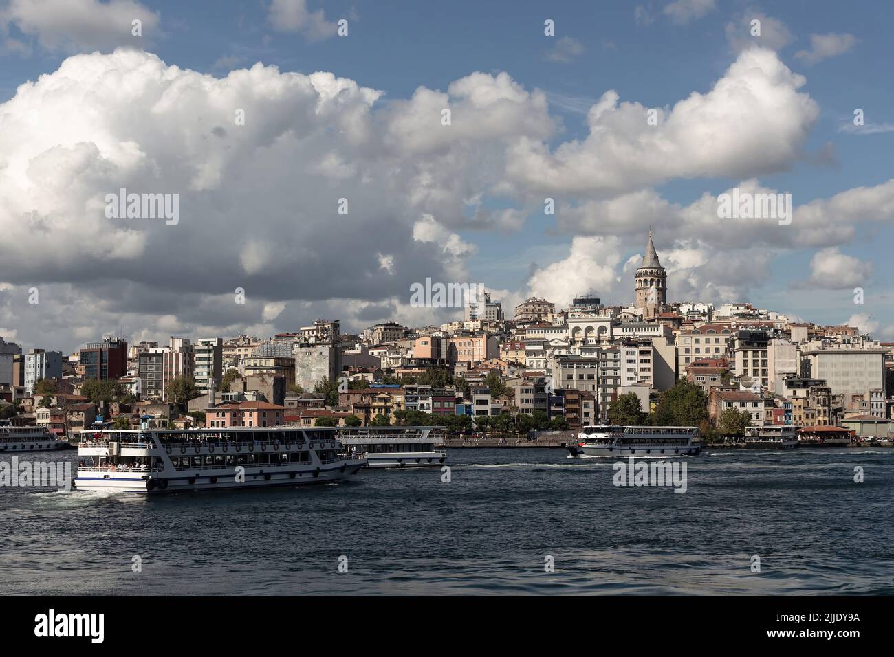 Vista delle barche del tour nella zona del Corno d'Oro del Bosforo di Istanbul. La torre Galata e il quartiere Beyoglu sono sullo sfondo. È una giornata estiva soleggiata. Foto Stock