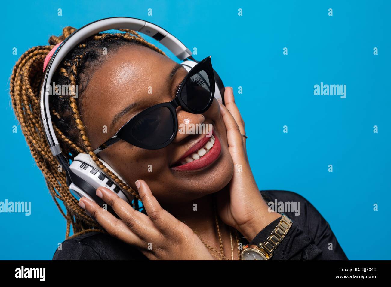 Un primo piano di una giovane donna con pelle scura che ascolta musica. Foto Stock