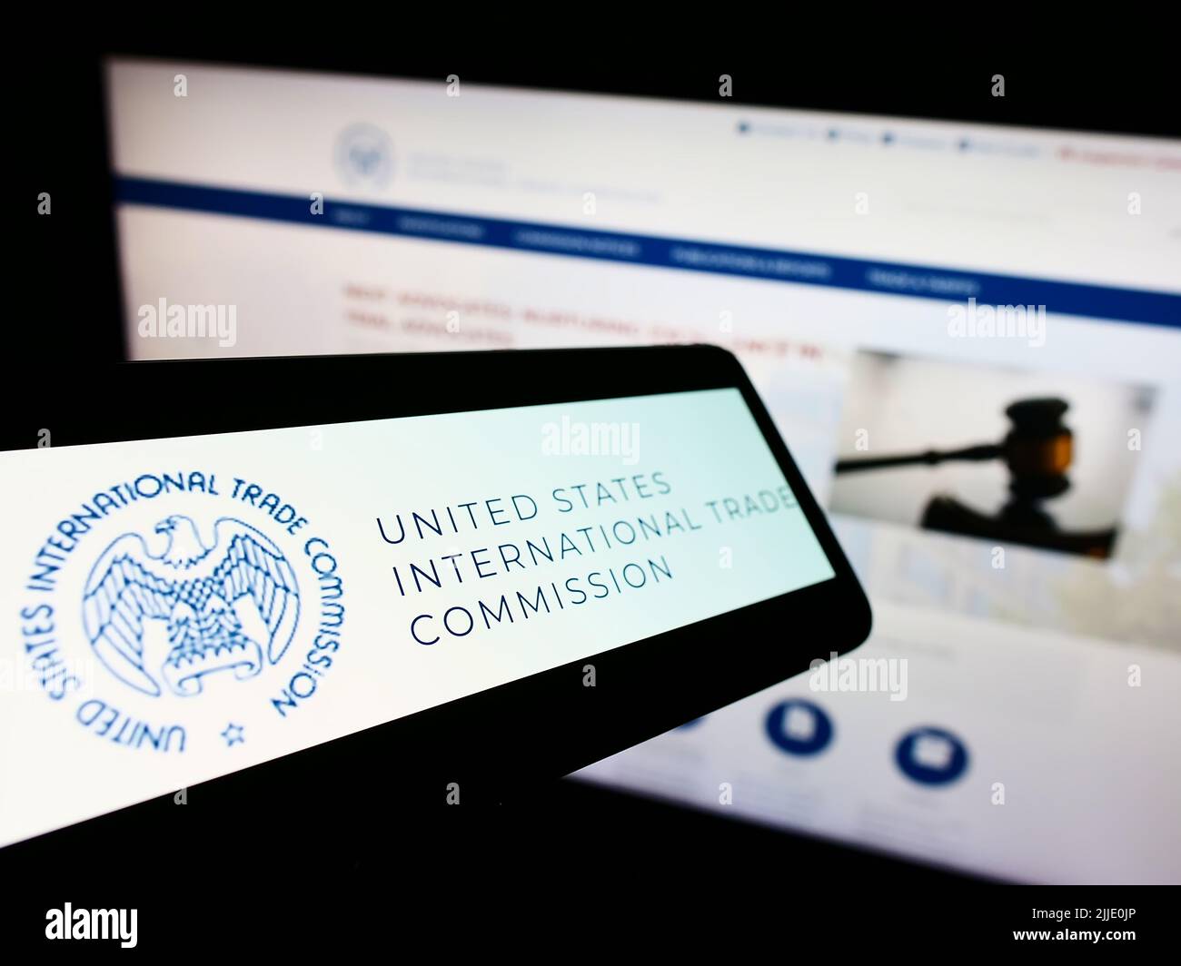Smartphone con logo della American International Trade Commission (USITC) sullo schermo di fronte al sito Web. Messa a fuoco al centro-sinistra del display del telefono. Foto Stock