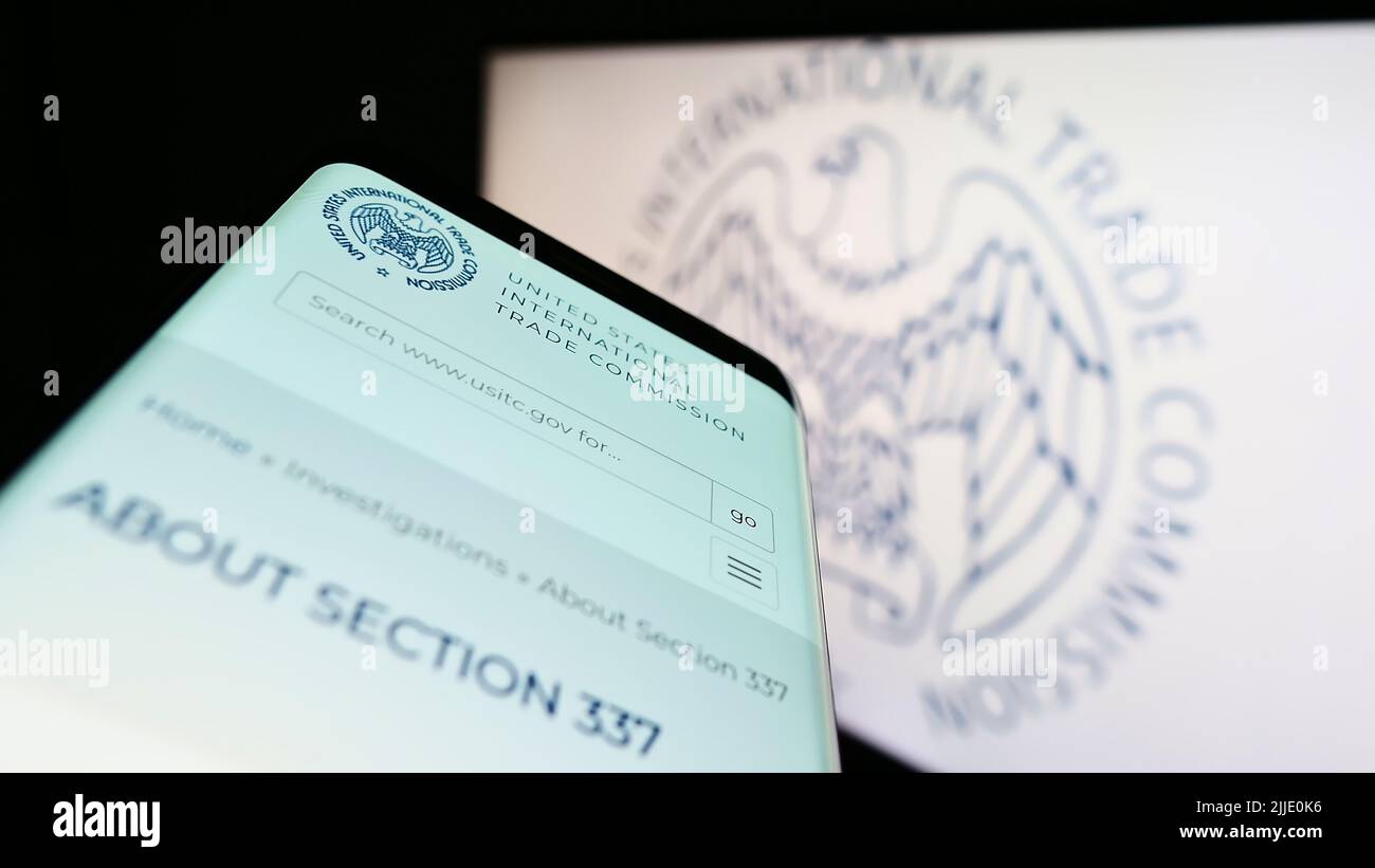 Telefono cellulare con pagina web della US International Trade Commission (USITC) sullo schermo di fronte al logo. Mettere a fuoco sulla parte superiore sinistra del display del telefono. Foto Stock