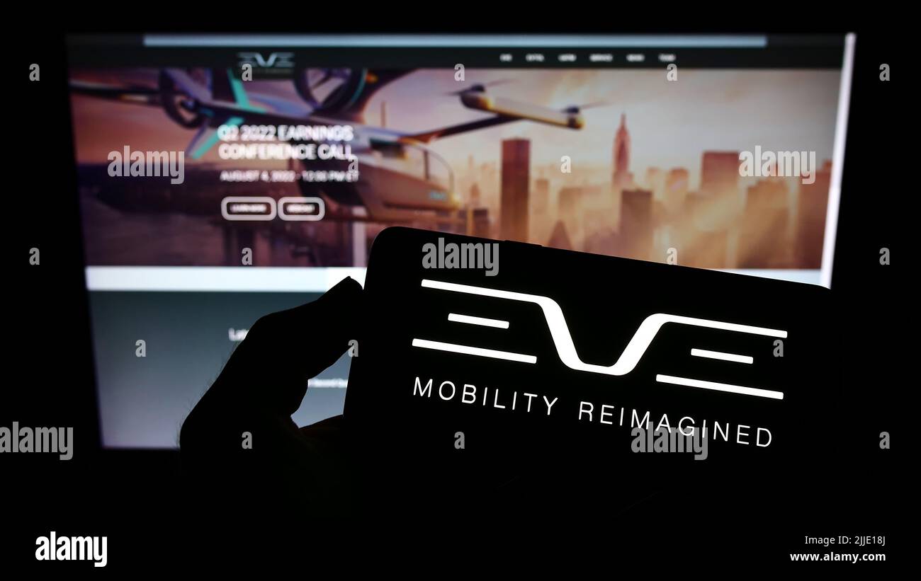 Persona che tiene lo smartphone con il logo della società Eve Holding Inc. (Eve Air Mobility) sullo schermo di fronte al sito Web. Mettere a fuoco sul display del telefono. Foto Stock
