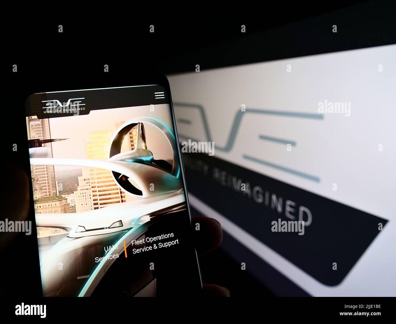 Persona che tiene il cellulare con il sito web della società Eve Holding Inc. (Eve Air Mobility) sullo schermo di fronte al logo. Concentrarsi sul centro del display del telefono. Foto Stock