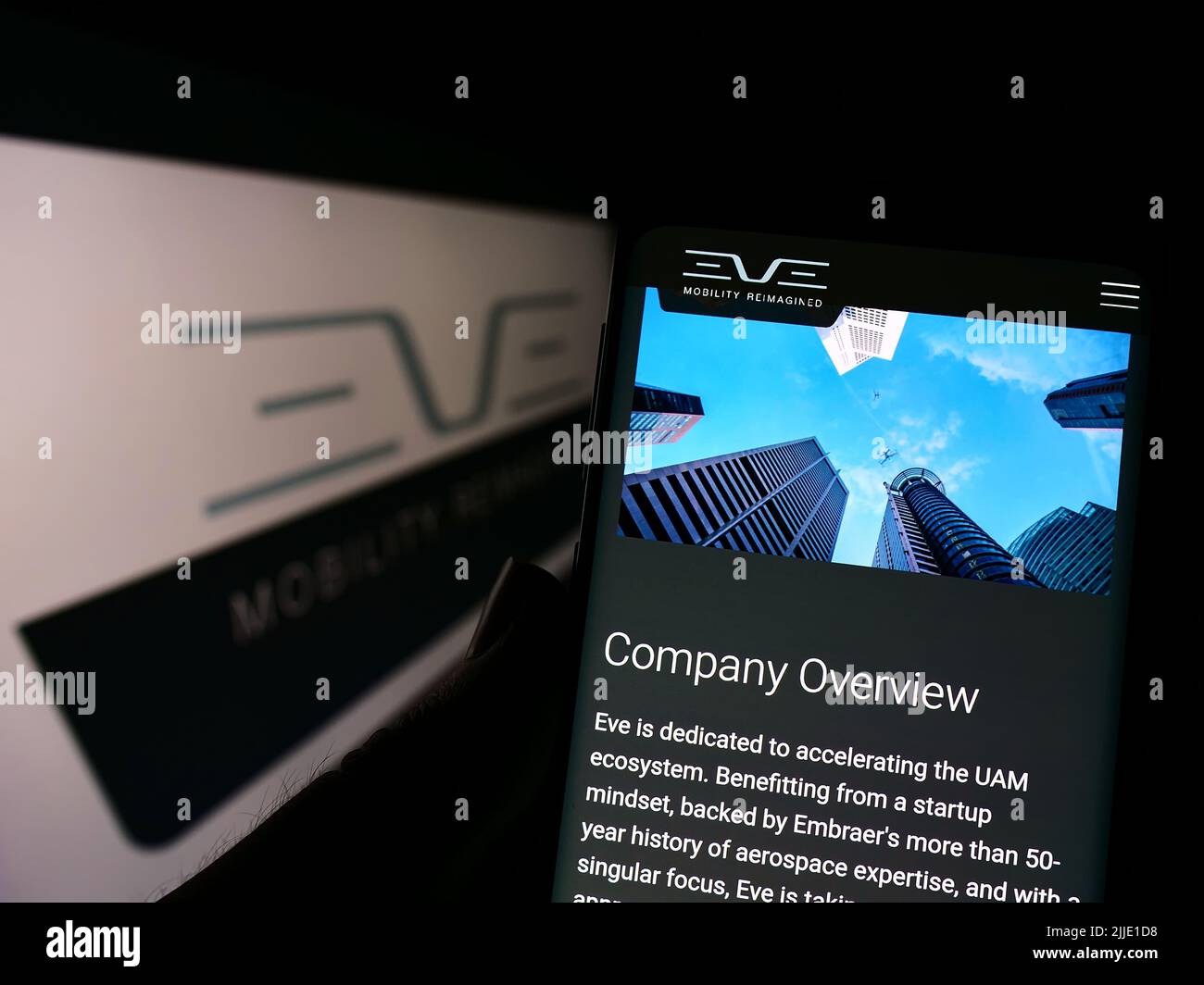Persona che tiene lo smartphone con la pagina Web della società Eve Holding Inc. (Eve Air Mobility) sullo schermo davanti al logo. Concentrarsi sul centro del display del telefono. Foto Stock