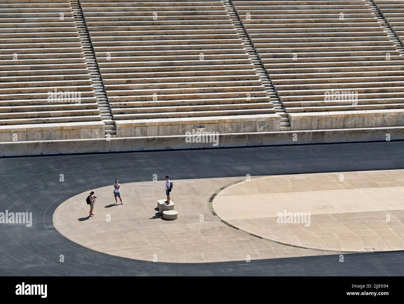 Atene, Grecia - Maggio 2022: Turista avendo la sua foto scattata mentre si alza su e replica dei vincitori podio presso lo storico Stadio Olimpico della città Foto Stock