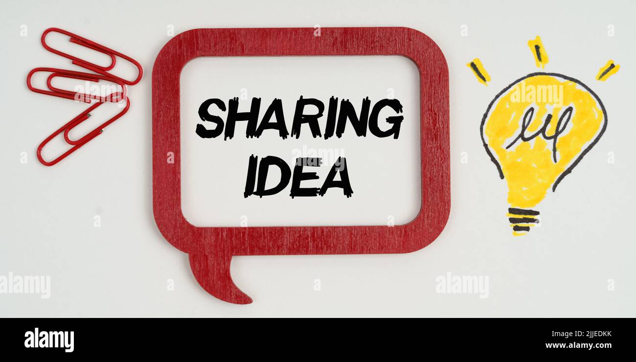 Idea e concetto di business. Sulla carta, un disegno di una lampada, graffette di carta e un segno con l'iscrizione - idea di condivisione Foto Stock