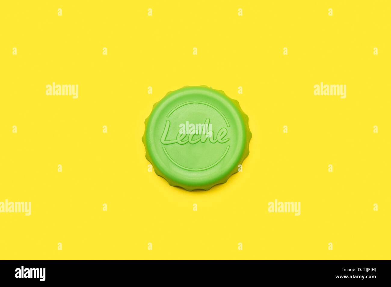 Coperchio di plastica verde con la parola leche su sfondo giallo (traduzione - latte) Foto Stock