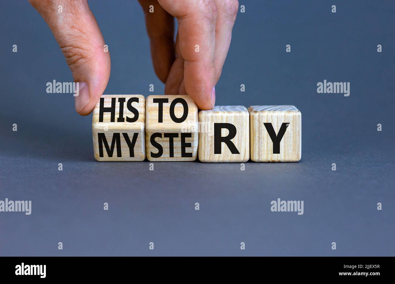 Storia contro mistero simbolo. Concetto parole Storia e mistero su cubi di legno. Mano dell'uomo d'affari. Bello sfondo grigio tavolo. Affari, Ciao Foto Stock