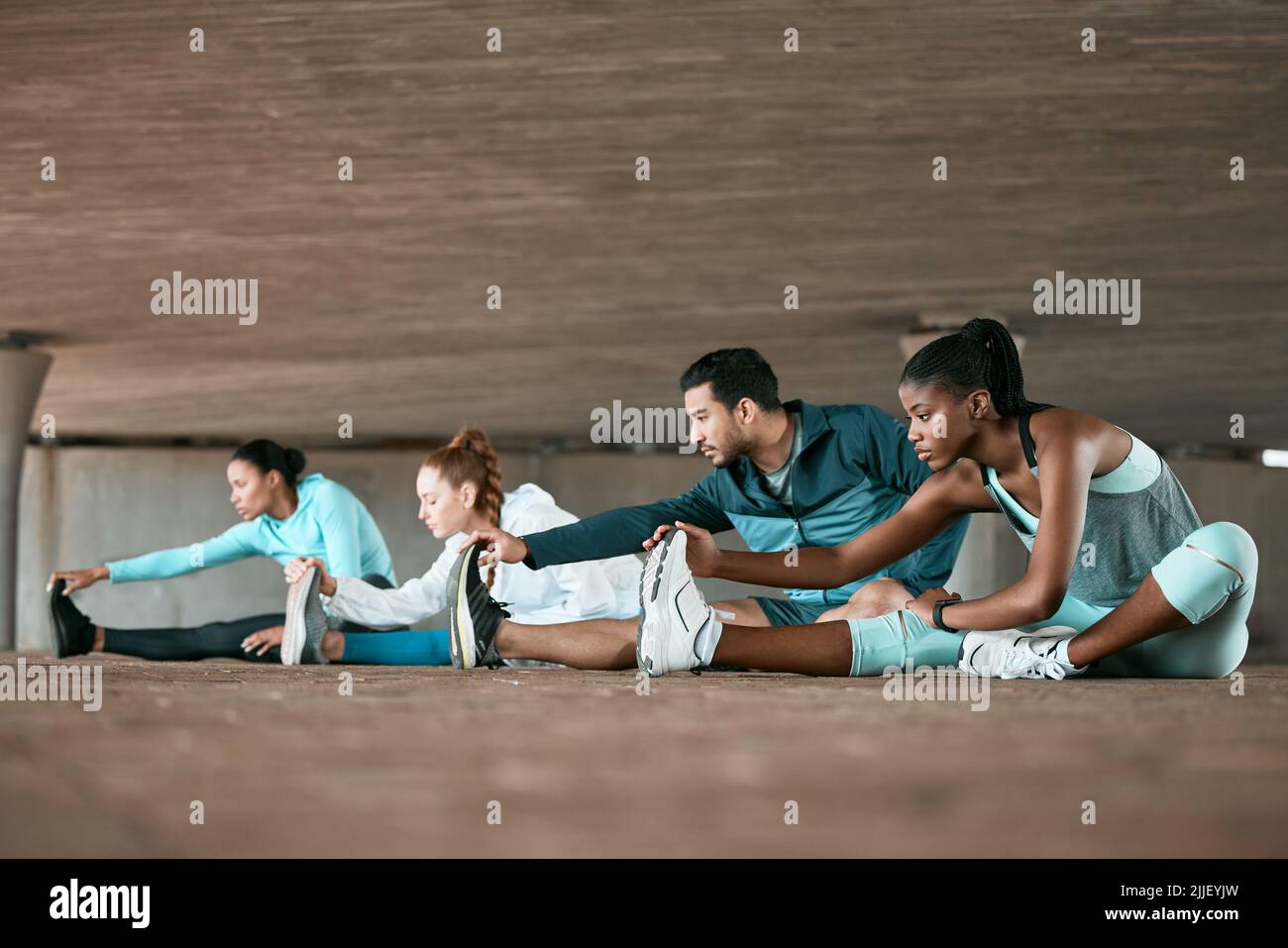Siamo entusiasti di iniziare il nostro percorso di fitness. Un gruppo di amici che si allungano insieme prima di allenarsi. Foto Stock