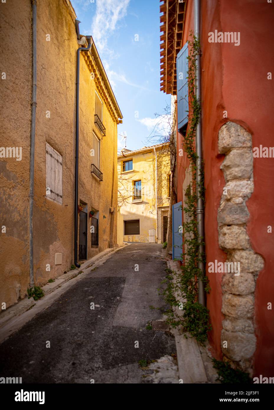Vecchia strada del villaggio di Gruissan, Francia meridionale, con pareti beige e rosa così come persiane blu, preso in un inverno soleggiato a fine Foto Stock
