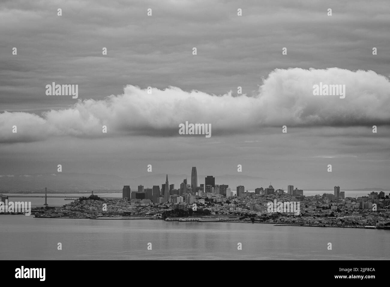 Un'immagine in scala di grigi del paesaggio urbano di San Francisco sotto un enorme paesaggio nuvoloso Foto Stock