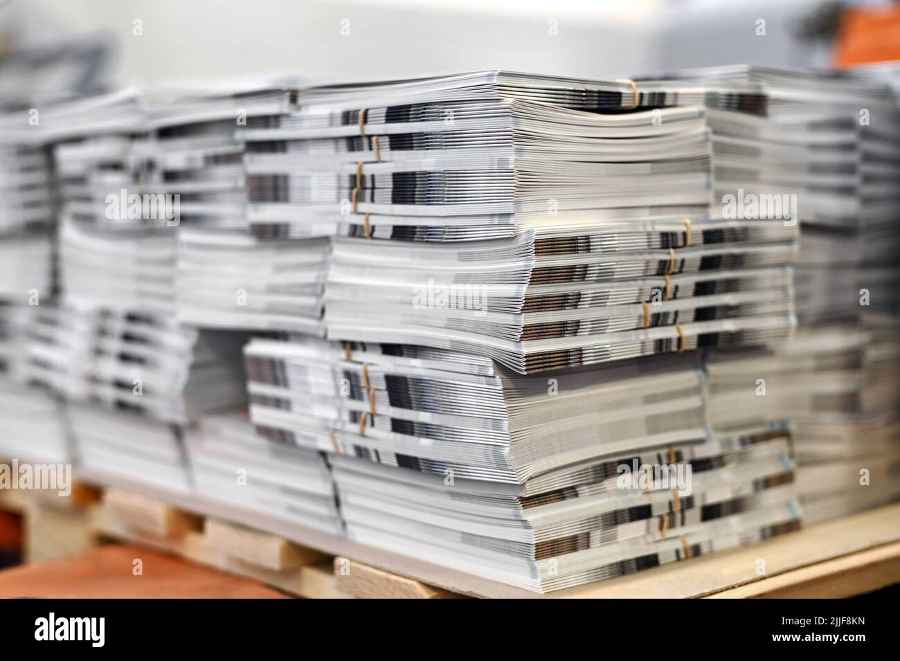 Soft focus di fogli di cataloghi appena stampati impilati su pallet di legno in laboratorio tipografico Foto Stock