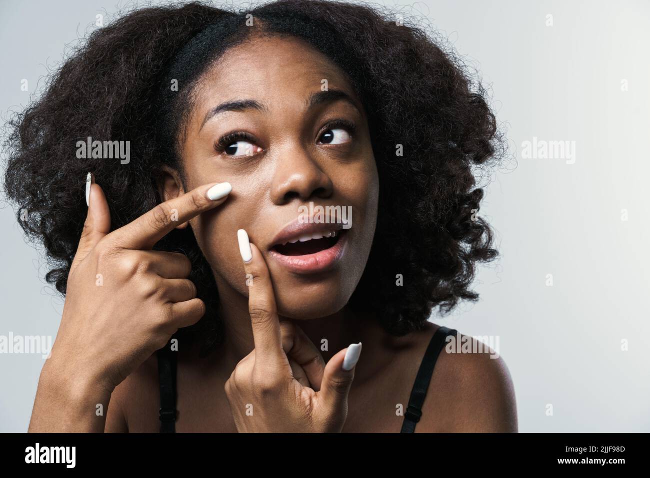 Giovane donna nera in reggiseno che stringe pimple sul suo volto isolato su  sfondo bianco Foto stock - Alamy