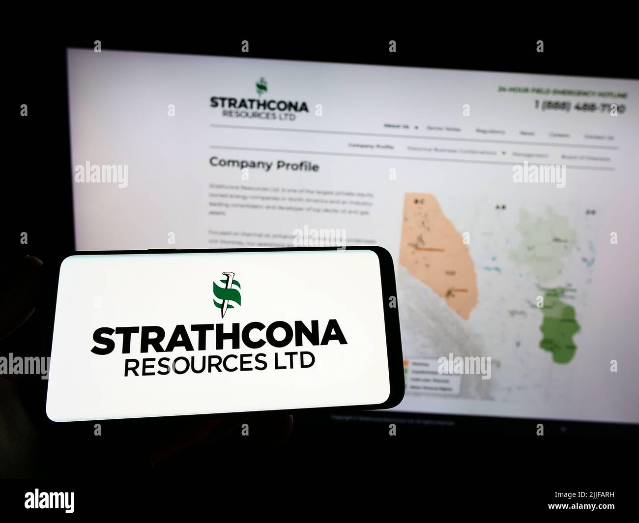 Persona che tiene smartphone con il logo della compagnia petrolifera canadese Strathcona Resources Ltd. Sullo schermo di fronte al sito web. Mettere a fuoco sul display del telefono. Foto Stock