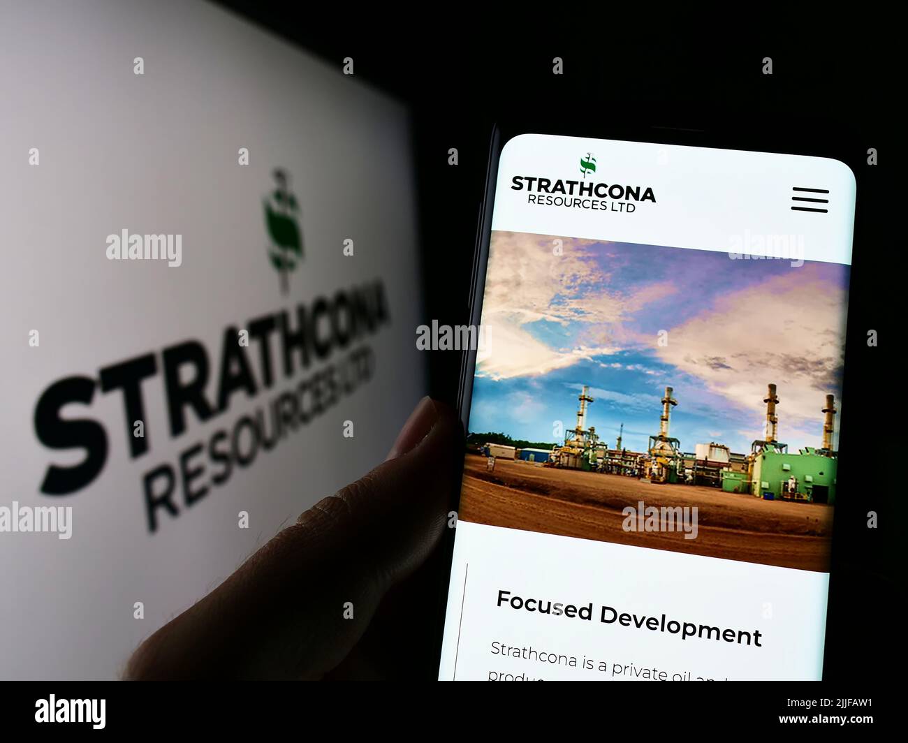 Persona che tiene smartphone con pagina web della compagnia petrolifera canadese Strathcona Resources Ltd. Su schermo con logo. Concentrarsi sul centro del display del telefono. Foto Stock