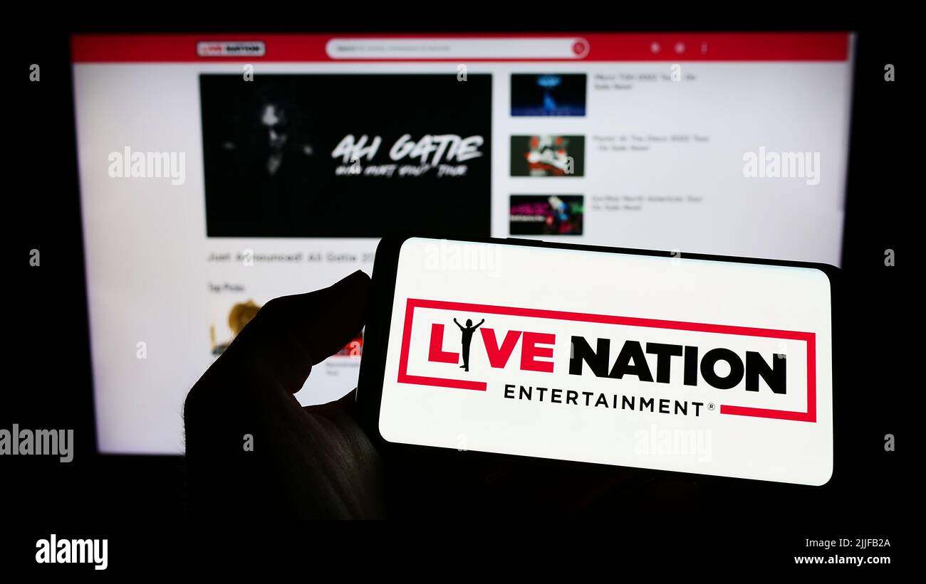 Persona che tiene il cellulare con il logo della società statunitense Live Nation Entertainment Inc. Sullo schermo di fronte alla pagina web aziendale. Mettere a fuoco sul display del telefono. Foto Stock
