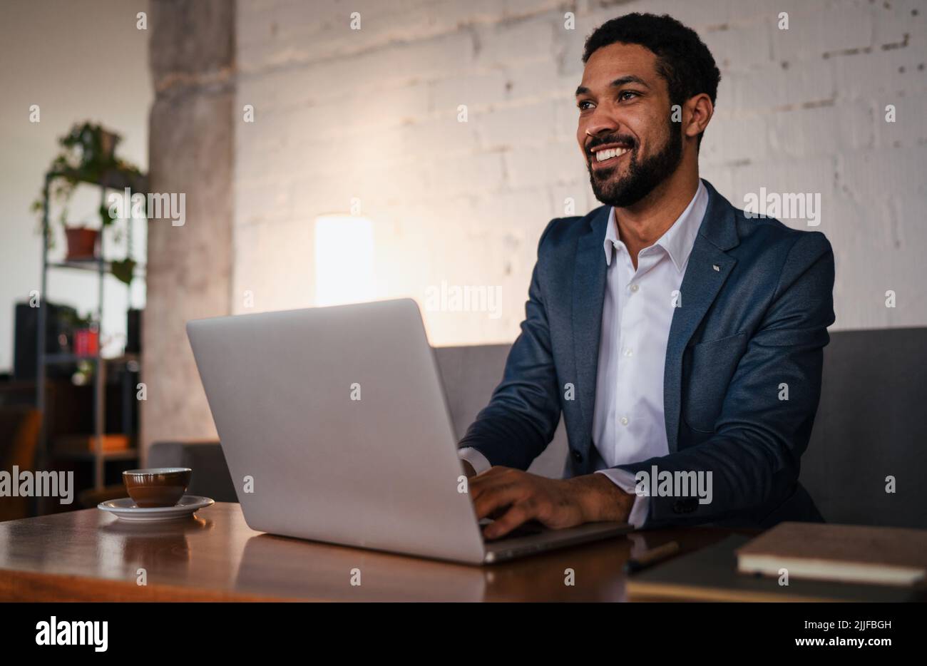 Felice uomo d'affari giovane che ha caffè e che fa il suo lavoro in caffè. Foto Stock