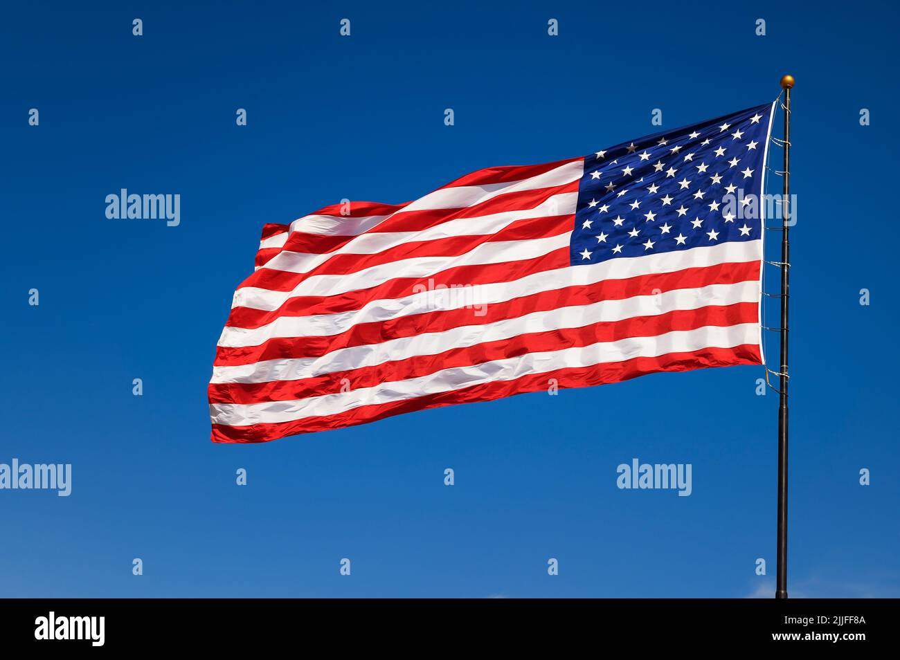 Bandiera degli Stati Uniti che sventola nel vento contro un cielo blu senza nuvole Foto Stock