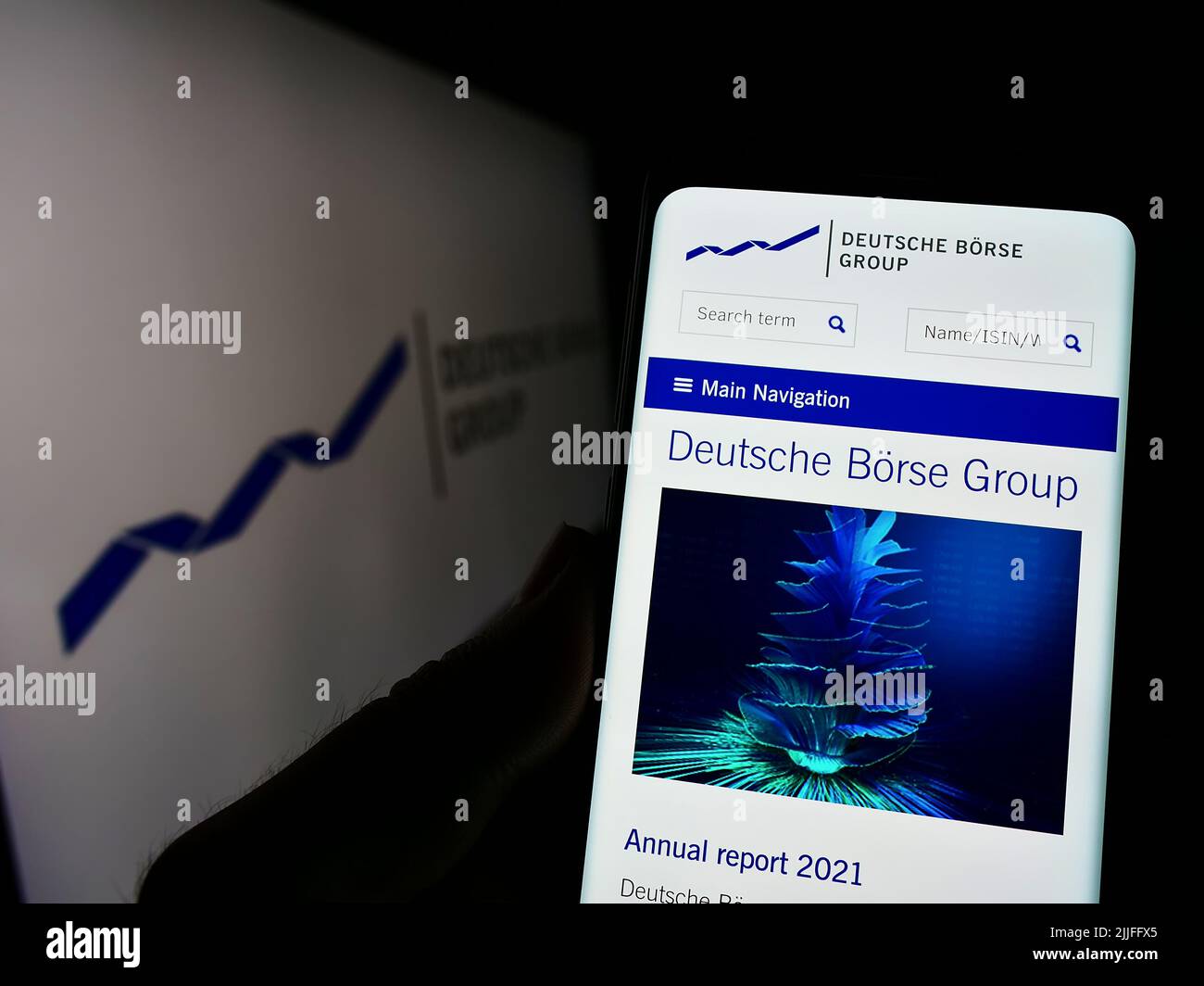 Persona che detiene il cellulare con il sito web della società finanziaria tedesca Deutsche Borse AG sullo schermo di fronte al logo. Concentrarsi sul centro del display del telefono. Foto Stock