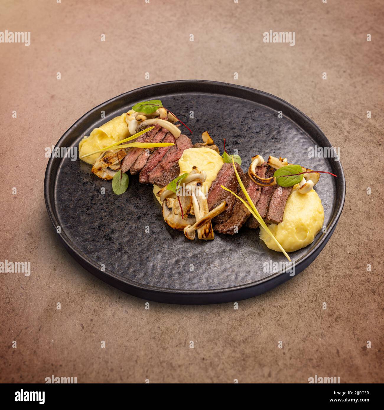 Fettine di bistecca di manzo servite con purè di patate e funghi alla griglia Foto Stock