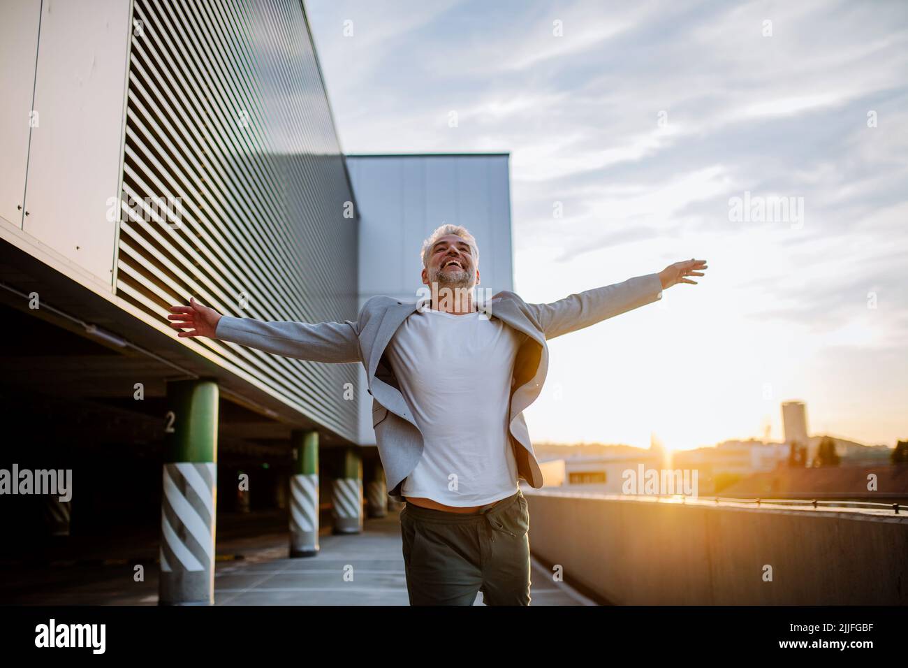 Ritratto di felice uomo d'affari maturo energico con braccia estese bilanciamento sul muro , sensazione di libertà, lavoro vita equilibrio concetto. Foto Stock