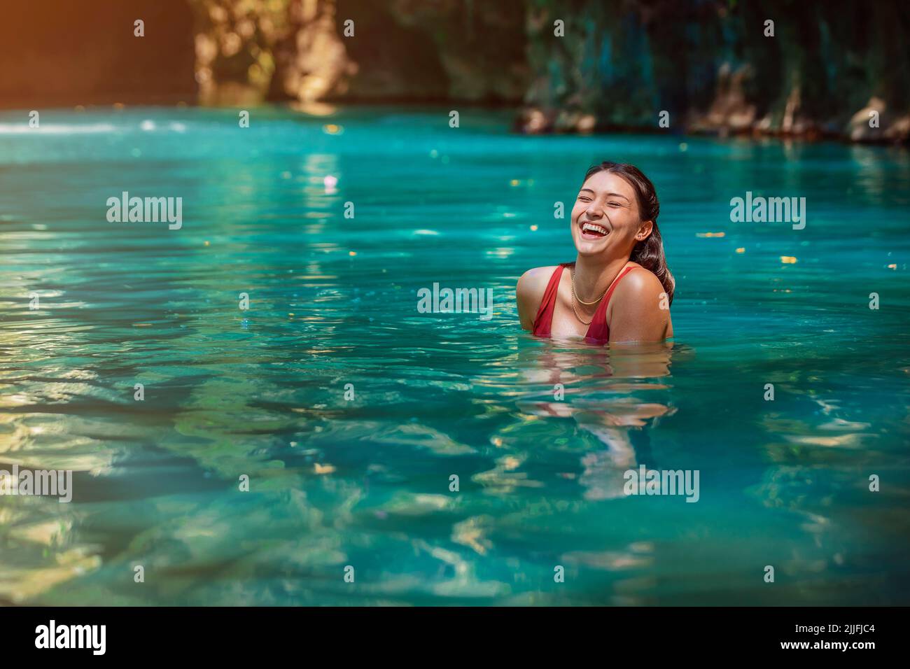 Giovane donna latina in piedi nelle acque blu verde del Rio Blanco in Costa Rica Foto Stock