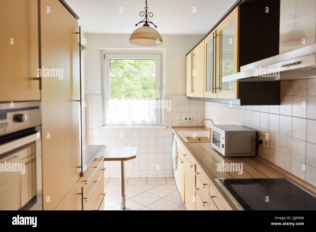 Angolo cottura con forno a microonde in una piccola e luminosa cucina con finestra Foto Stock