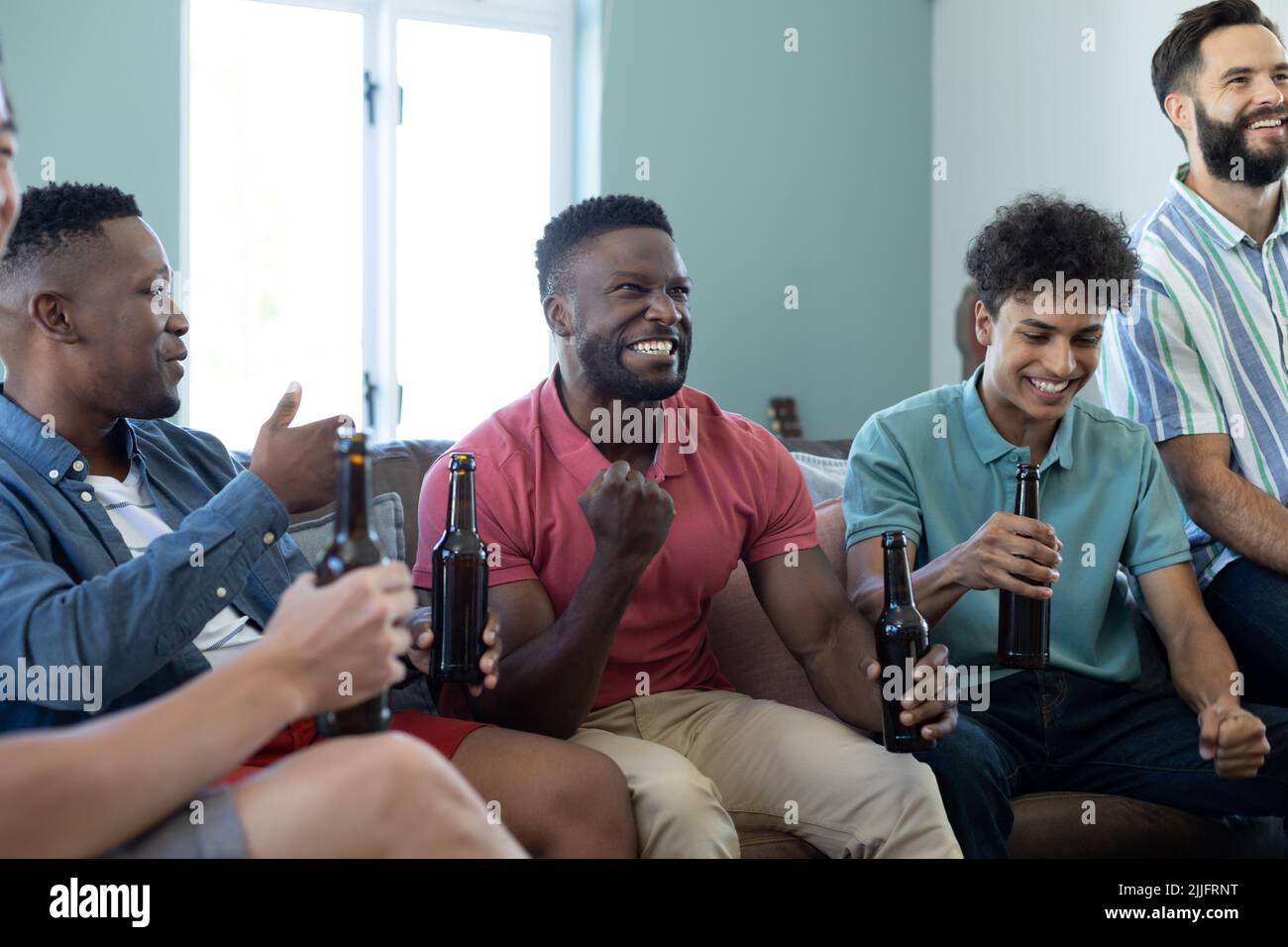 Allegro uomo multirazziale gesturing nella vittoria mentre godendo la partita con gli amici maschi a casa Foto Stock