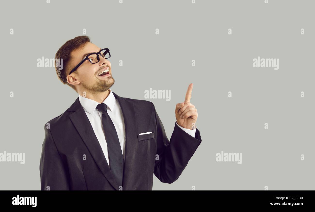 Divertente uomo d'affari pazzo pensa di una buona idea di affari, punta il suo dito su e sorride Foto Stock