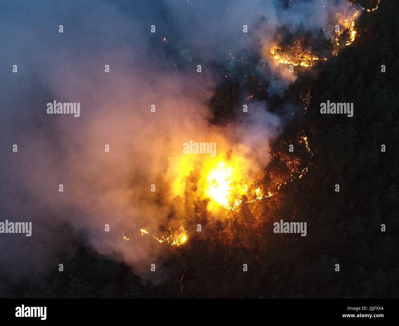 Vista panoramica aerea di un incendio forestale di notte, il fumo pesante provoca inquinamento dell'aria, e fuoco in piena luce. Un'epica ripresa cinematografica di droni di un disastro naturale. Foto Stock