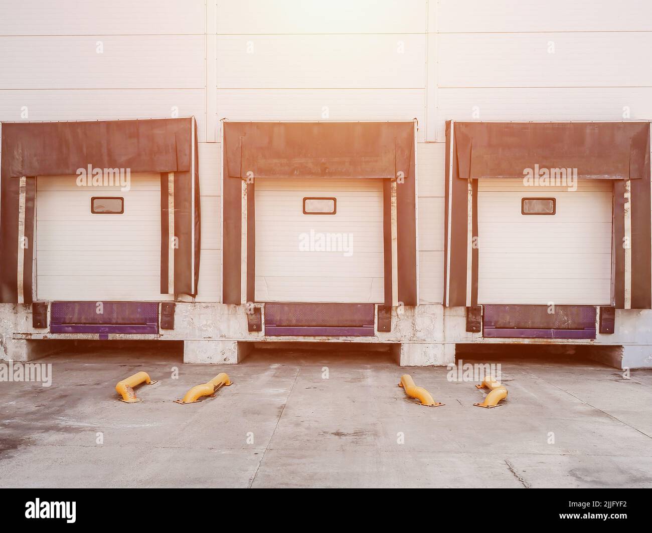 In un edificio bianco del magazzino, sono presenti tre porte automatiche per lo scarico delle merci. Foto Stock