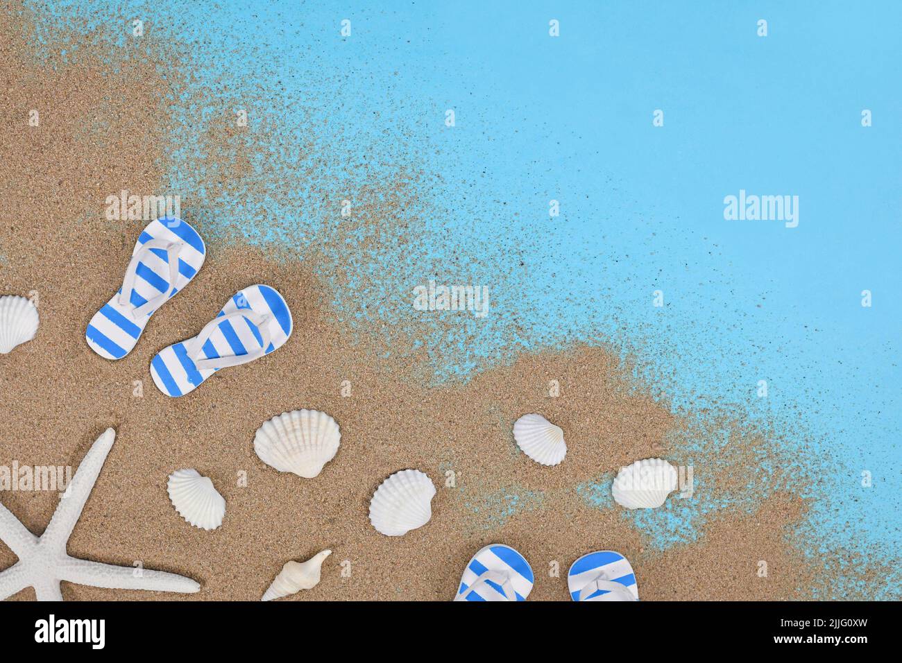 Scarpe estive, conchiglie, stelle marine e sabbia in un angolo di sfondo blu Foto Stock