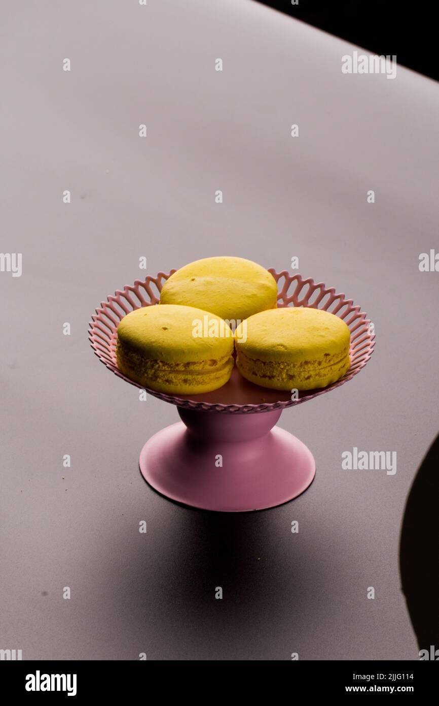Macaroni gialli su sfondo nero pasta francese. Pila di macaron giallo con isolato su sfondo nero scuro. Macaroon. Foto Stock