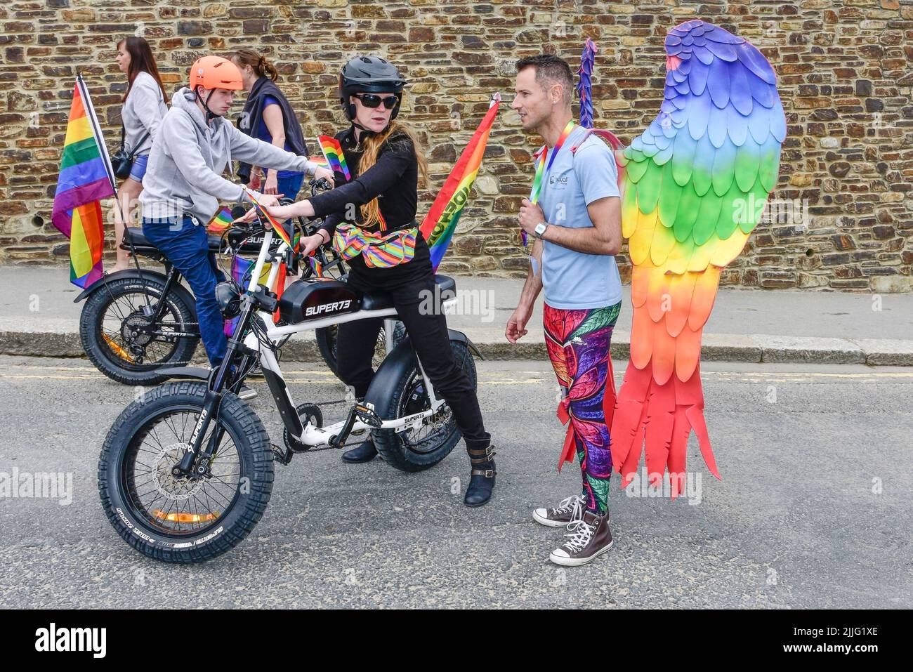 I piloti che usano biciclette elettriche Super 73 all'inizio della vivace e colorata Cornovaglia, sono orgogliosi della sfilata Pride nel centro di Newquay, nel Regno Unito. Foto Stock