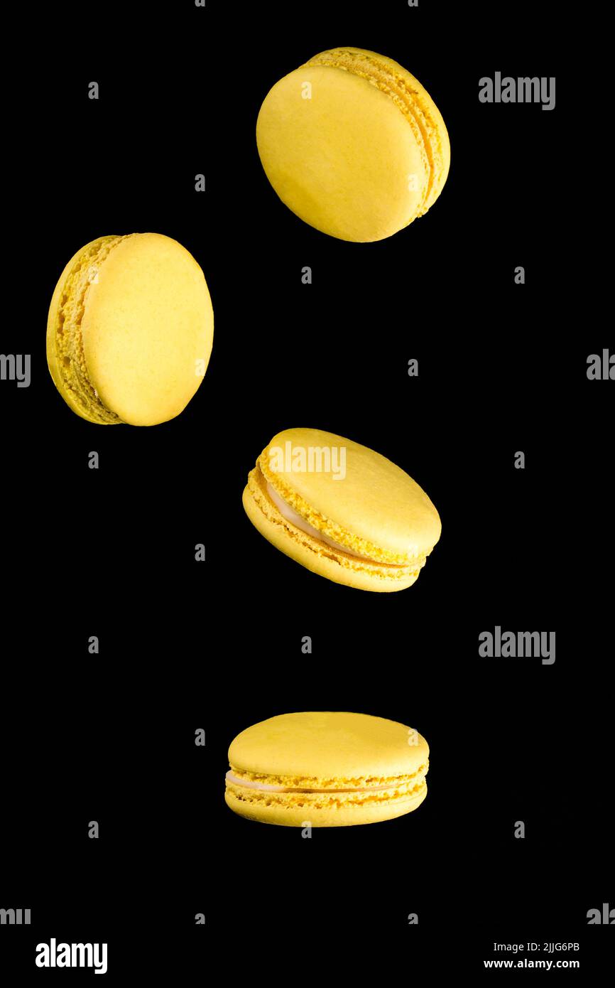 Macaroni gialli su sfondo nero pasta francese. Pila di macaron giallo con isolato su sfondo nero scuro. Macaroon. Foto Stock