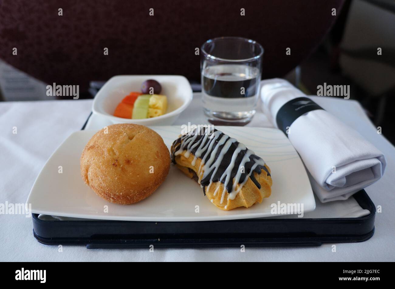 il pacchetto snack dell'aeroplano include pane al cioccolato, acqua minerale, frutta e tessuti bianchi Foto Stock