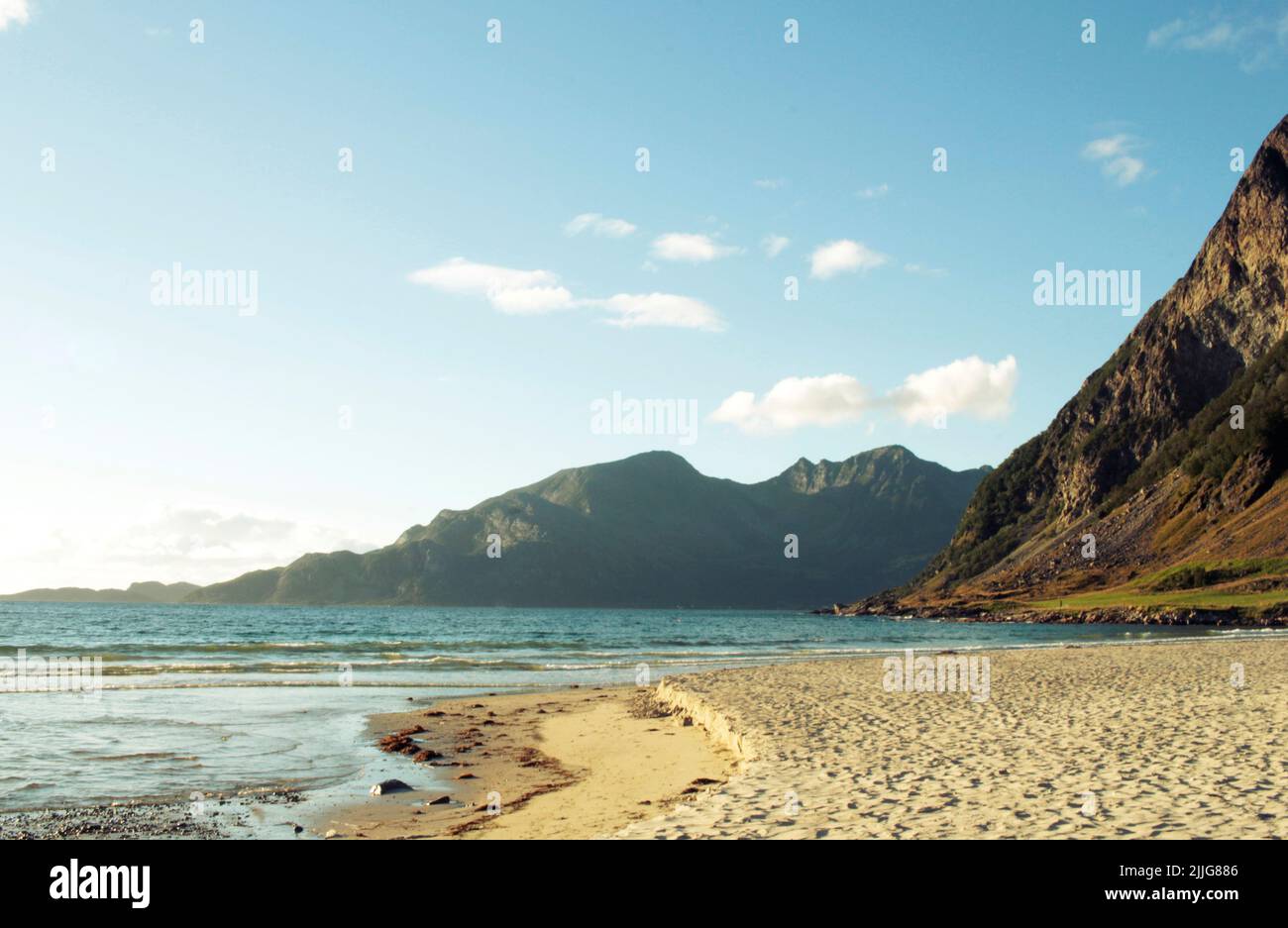 Spiagge sabbiose del mare norvegese in una giornata estiva con cielo azzurro e montagne torreggianti. Foto Stock