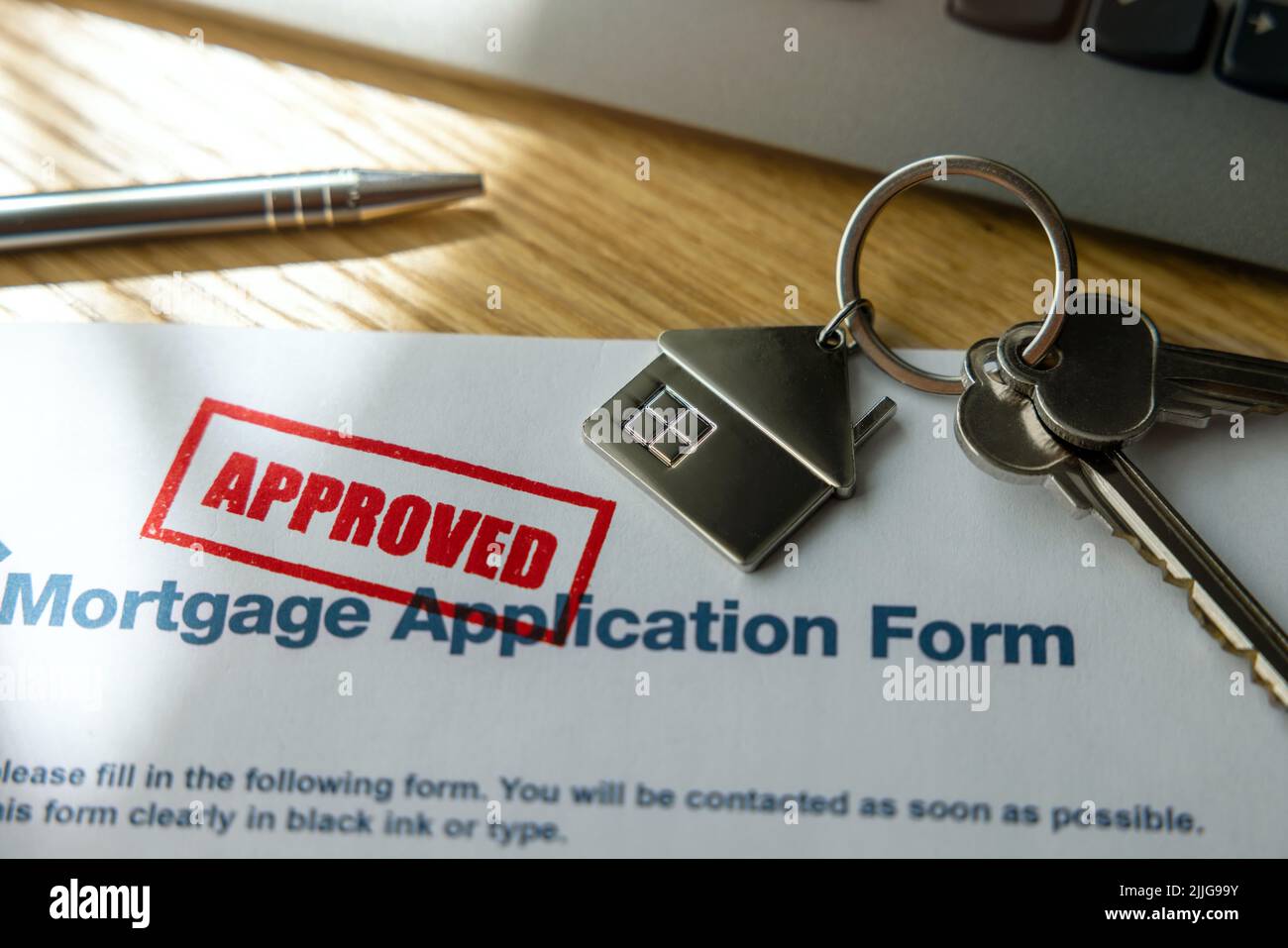 modulo di domanda di prestito ipotecario approvato e nuove chiavi della casa sulla tabella dell'ufficio della banca Foto Stock