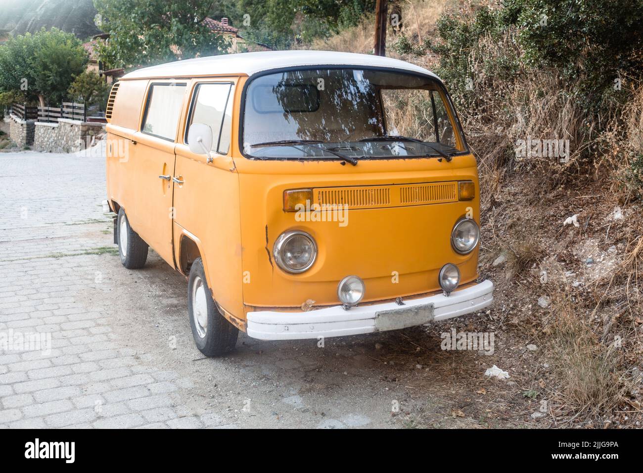 Un vecchio hippie arrugginito giallo caldo bus, un piccolo furgone di viaggio su una strada Foto Stock