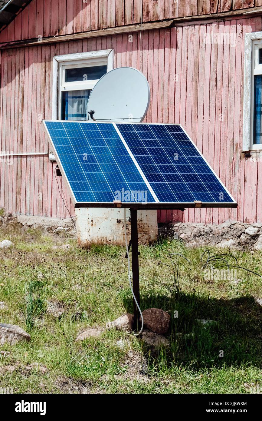 Piccolo pannello solare vicino a vecchia casa di legno. Foto Stock