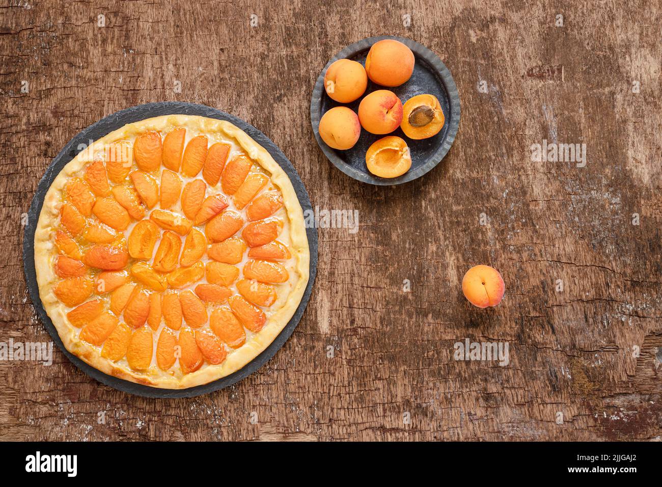 Pizza di frutta con pesche su un tavolo scuro in legno, torta vegetariana estiva fatta in casa, vista dall'alto Foto Stock