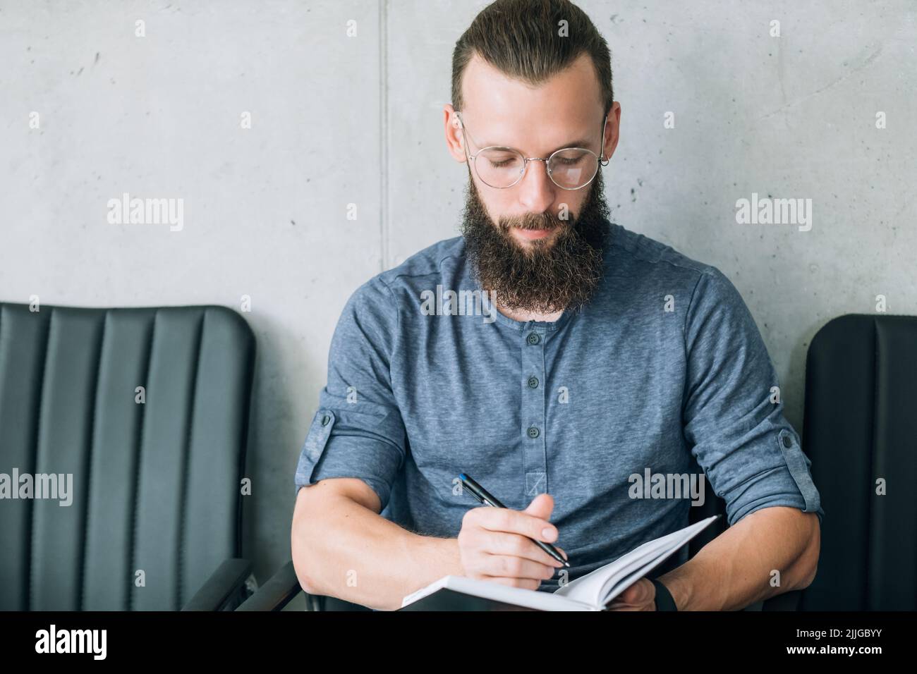 uomo seduto fila sedie scrivere intervista domanda di lavoro Foto Stock