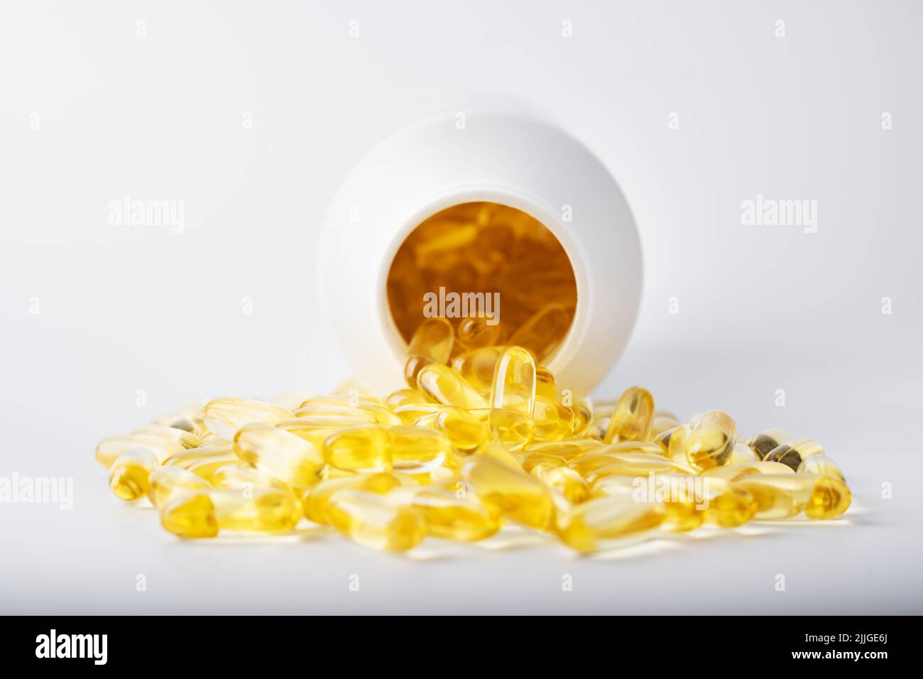 Capsule di olio di pesce giallo in un guscio di gelatina vicino al vaso bianco. Vitamine e integratori dietetici. Concetto di salute Foto Stock