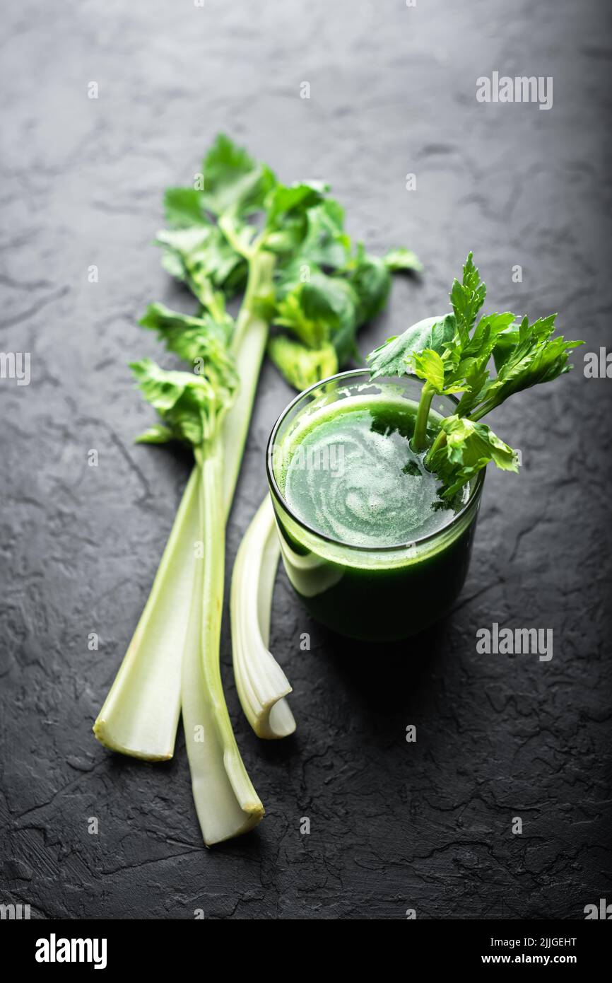 Sedano succo verde fresco in vetro su sfondo nero. Concetto di cibo vegetariano sano Foto Stock