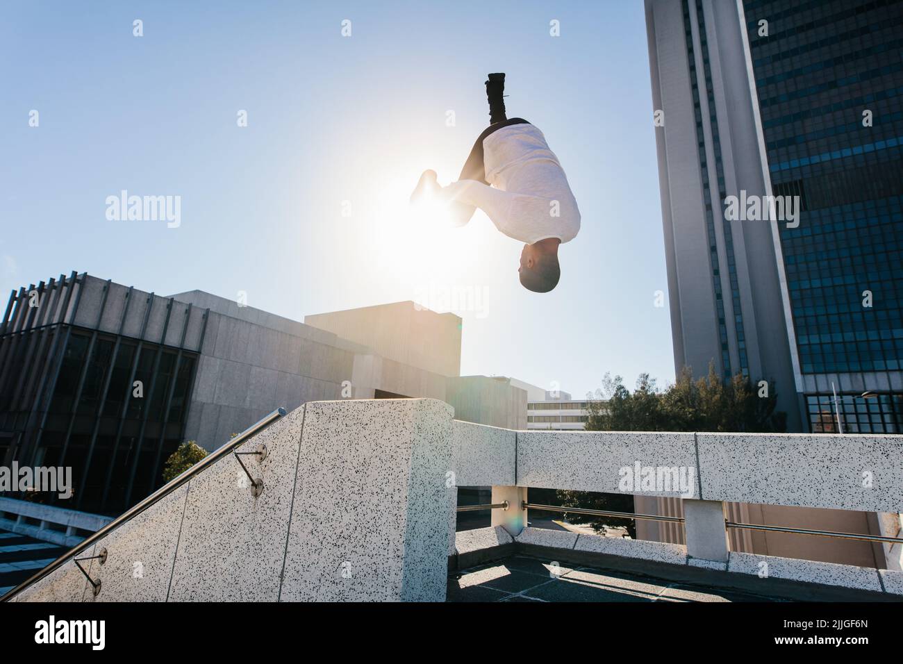 Uomo atletico che pratica il parkour e la corsa libera facendo un frontflip da un ostacolo all'aperto. Giovane sportivo che pratica attività sportive estreme o Foto Stock