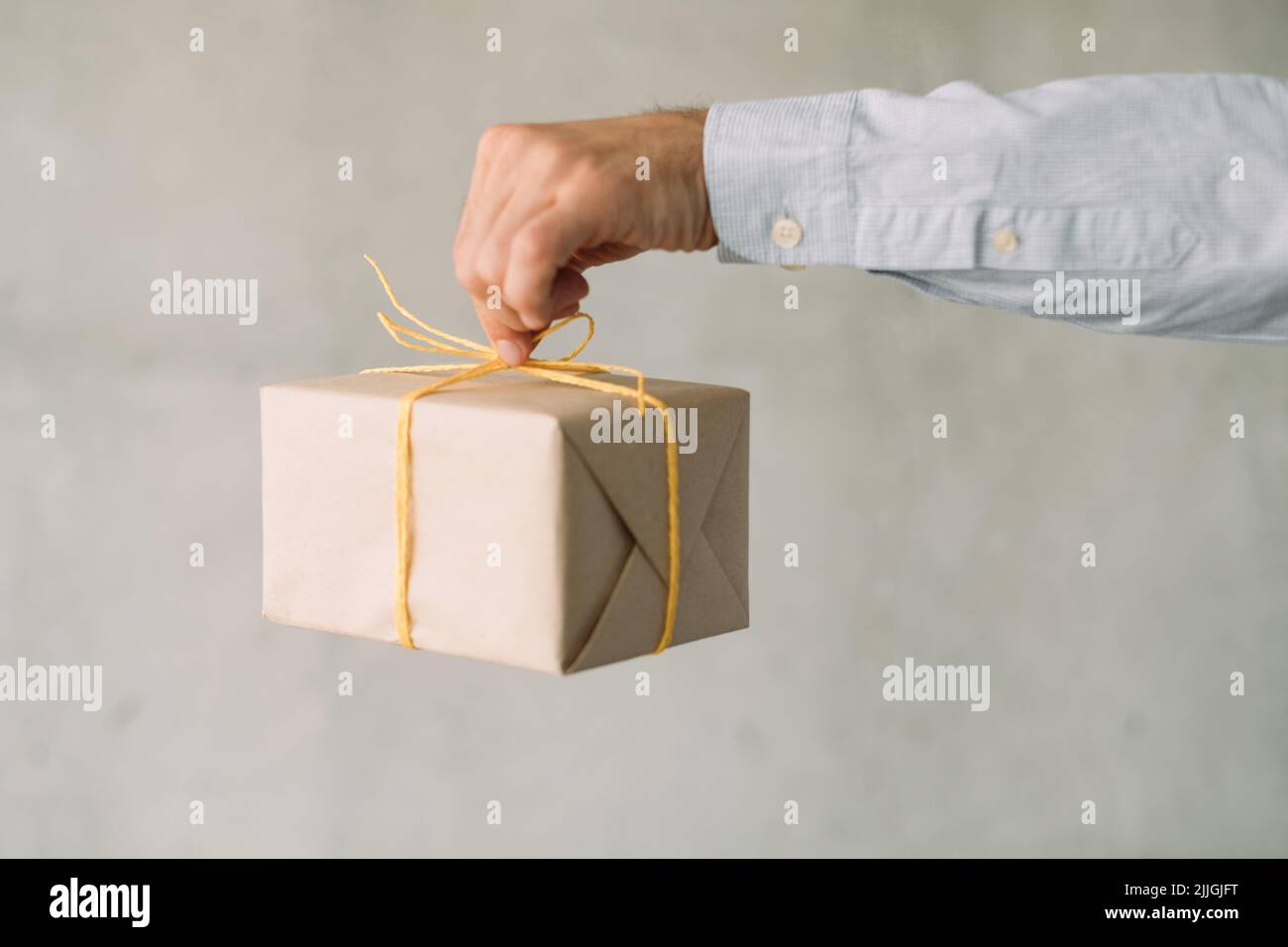 consegna merce servizio beige scatola regalo mano uomo Foto Stock